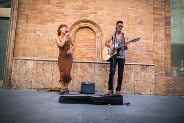 Buskers playing on a busy street in Seville, Spain. Guitarist man and singer woman.