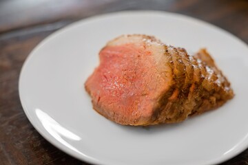 Homemade sliced grilled medium rare beef steak serving on white plate. 