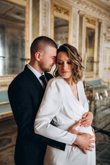 Portrait of the groom and the pregnant bride. Newlyweds in the ceremony hall.