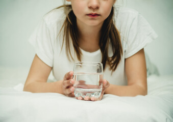 teenage girl with a glass of water on the bed close-up