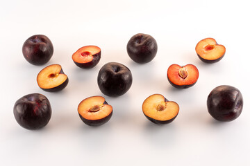 plums whole and cut in half are laid out on a white background