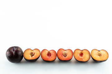 five half plums and one whole plum on a white background