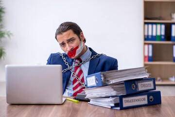Chained male employee unhappy with excessive work in the office