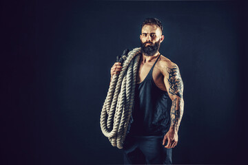 Fototapeta na wymiar Muscular man working out with heavy rope. Photo of man with naked torso. Strength and motivation. 
