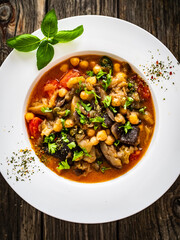 Delicious stew - aubergine with tomatoes and chickpeas on wooden table
