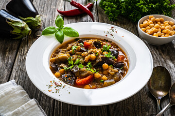 Delicious stew - aubergine with tomatoes and chickpeas on wooden table
