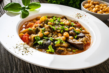 Delicious stew - aubergine with tomatoes and chickpeas on wooden table
