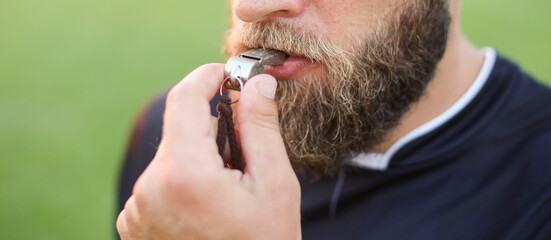 Close up of a football referee's whistle in his mouth