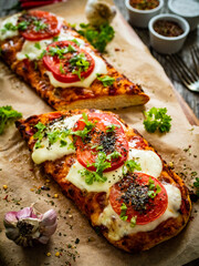 Focaccia - roasted sandwiches with mozzarella and  tomatoes on wooden background
