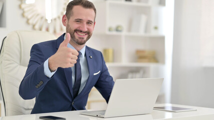 Positive Businessman with Laptop doing Thumbs Up 