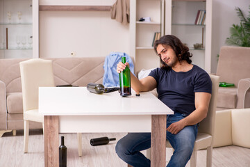 Young unemployed man drinking alcohol at home