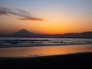 夕日に照らされる海岸と遠くに見える富士山