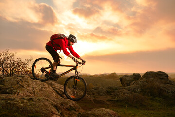 Fototapeta na wymiar Cyclist in Red Riding Bike on the Summer Rocky Trail at Sunset. Extreme Sport and Enduro Biking Concept.