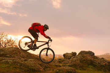 Cyclist in Red Riding Bike on the Summer Rocky Trail at Sunset. Extreme Sport and Enduro Biking...