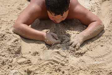 A boy plays in the sand on the seashore