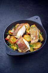 Modern style traditional fried skrei cod fish filet with fried potato, fruits and olives served as...