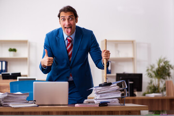 Young male employee holding plunger in funny concept