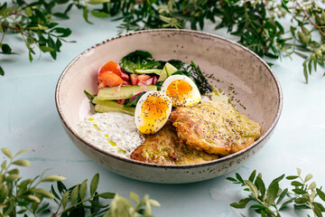 Side view on zucchini fritters with eggs sauces and vegetables