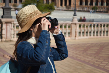 Young and beautiful asian tourist taking photos of monument with reflex camera during her vacation trip