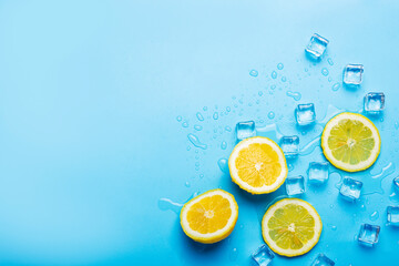 juicy fresh yellow lemon slices and ice cubes on a blue background. Top view, flat lay