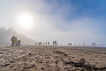 Crowd of people walking on a beach in sunny and foggy spring day. Stock photo