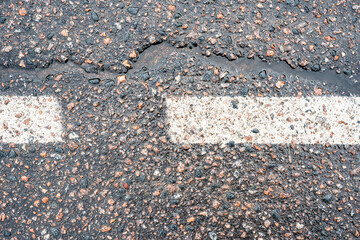 Old asphalt with a dividing line. After the rain. City environment. Top view close up.