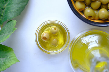 bottle of olive oil and fresh olive in a container on white background .
