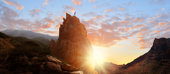 Woman free climbing freely hiking on rocks in the mountains at sunrise - landscape great hiking...