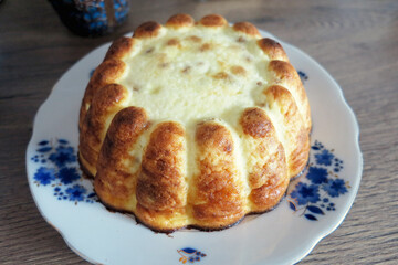 Cheese cake on a white plate on a wooden table. Curd casserole on a round dish. Selective focus