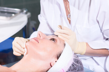 Fototapeta na wymiar Mature woman having jet peeling facial therapy treatment in beauty clinic