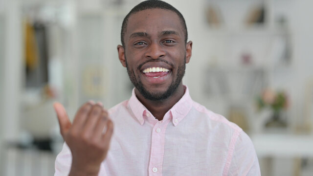 Portrait Of Cheerful African Man Pointing And Inviting 