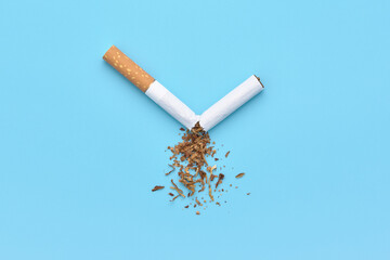A broken cigarette with scattered tobacco. Quit smoking concept. No tobacco day. Blue background,...
