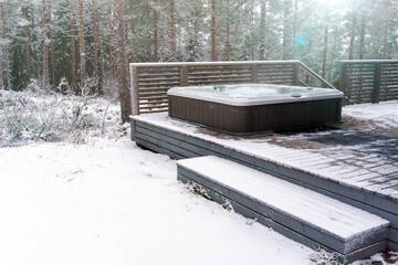 Modern outdoor hot tub on a wooden deck in a cold winter day, Salo, Finland.