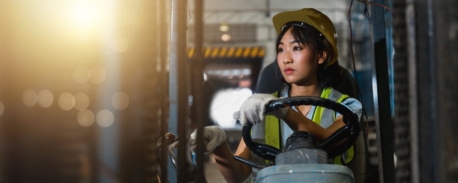 Asian beautiful woman driver drive fork lift car in industry with smiled, ability of girl and diversity of career wearing helmet in reflective vest working on vehicle