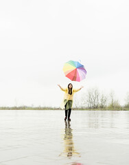 Funny woman catching colorful umbrella outdoors in the rain