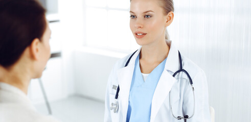 Fototapeta premium Woman - doctor consults her female patient in clinic. Medicine concept