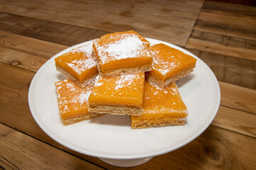 A pile of delicious lemon squares, home made tasty treats on a wooden kitchen table
