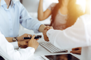 Fototapeta premium Two businessmen shaking hands in sunny office, close-up. Colleagues applauding of success meeting end