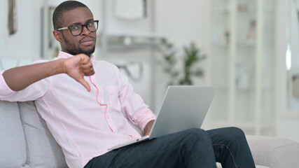 Thumbs Down by African Man with Laptop at Home 
