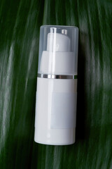 White plastic dispenser bottle lying on exotic leaf