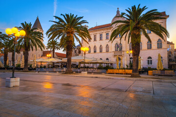Fototapeta na wymiar Promenade with street cafes and palm trees at dawn, Trogir