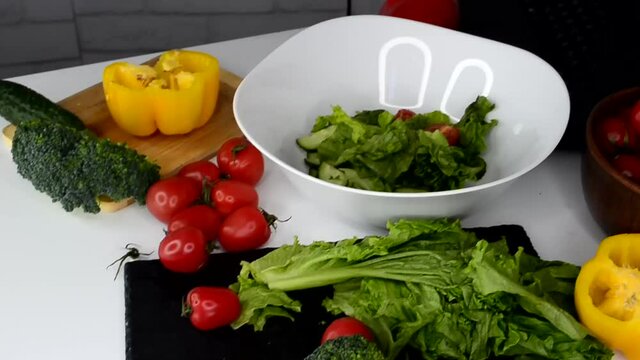 ingredients for making a fresh summer diet salad of broccoli, sweet pepper, cherry tomato and lettuce, preparing for online food courses using a laptop, the concept of blogging without people