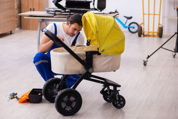 Young male repairer repairing perambulator indoors