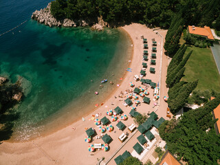 Colored sun umbrellas stand on the sand at the Royal Beach in Przno. View from above