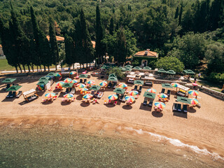 Aerial view of bright sun umbrellas on the royal beach in Przno against the backdrop of green trees