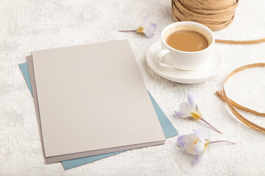 Gray paper sheet mockup with spring snowdrop crocus flowers and cup of coffee on gray concrete background. side view, close up.