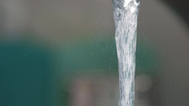Kitchen faucet runs at half power, shot in slow motion at 4K.