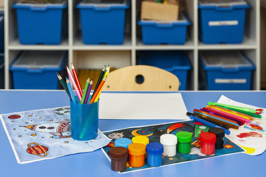Children's room with drawing facilities on the table. Pencils, markers, paints and drawing sheets are laid out on the children's table