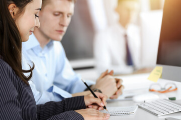 Obraz premium Business woman and man discussing questions while using computer at workplace in sunny office