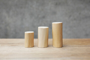 Thin and short barkless wooden log blocks on wooden table. Barkless cedar log set lined up individually in order of height on wooden background. 